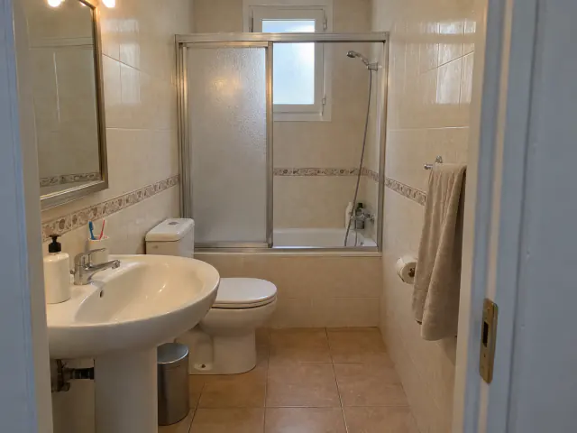 Antes: baño con bañera, mampara corredera de aluminio, lavabo de pie y azulejo con cenefa