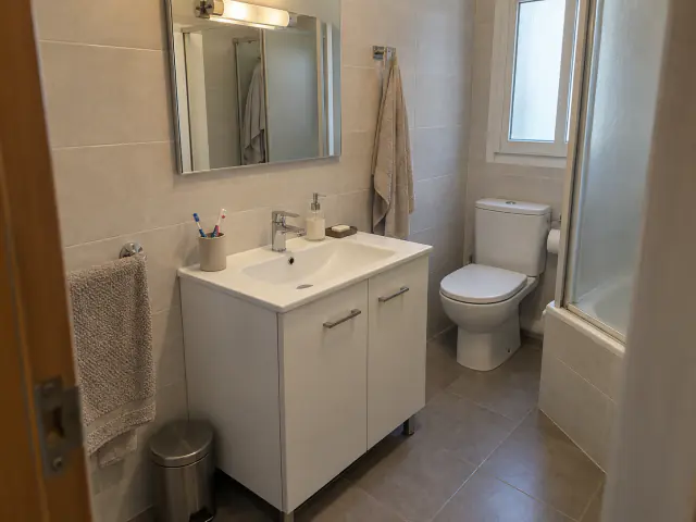 Antes: mueble de lavabo blanco con patas y espejo con aplique de luz